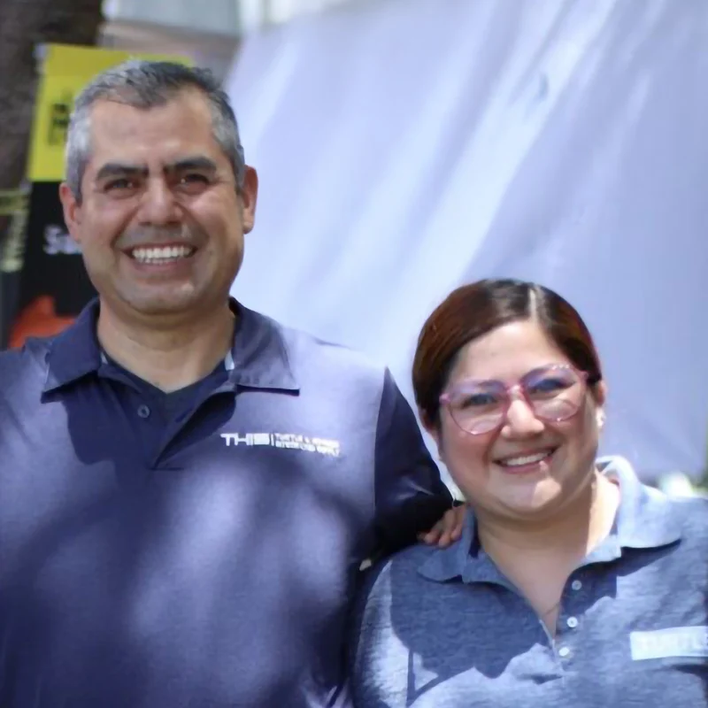 Two Turtle company employees in branded polo shirts smiling on site