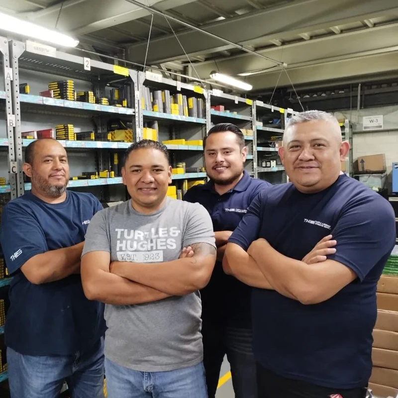 Four Turtle Company Employees in a warehouse setting with branded polo tops.