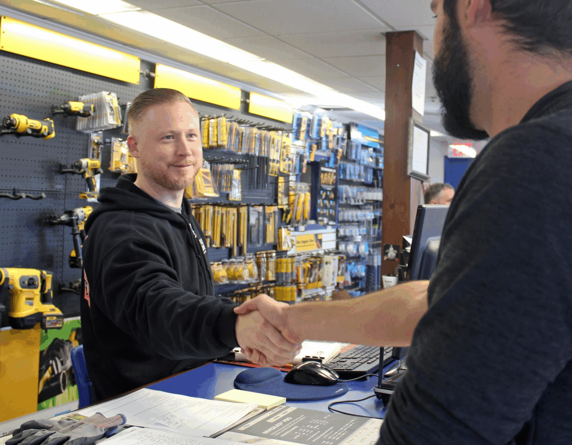 Two men shaking hands at hardware counter 