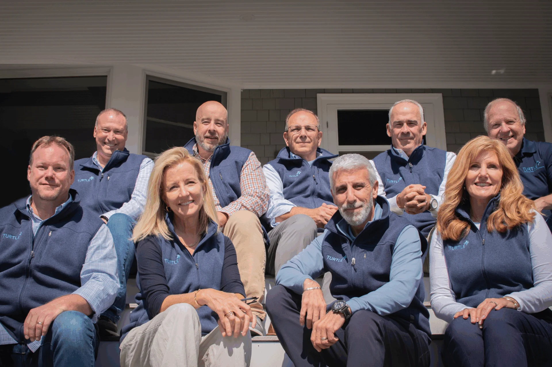 Group Photo of the leadership of Turtle Company sat together with branded vests