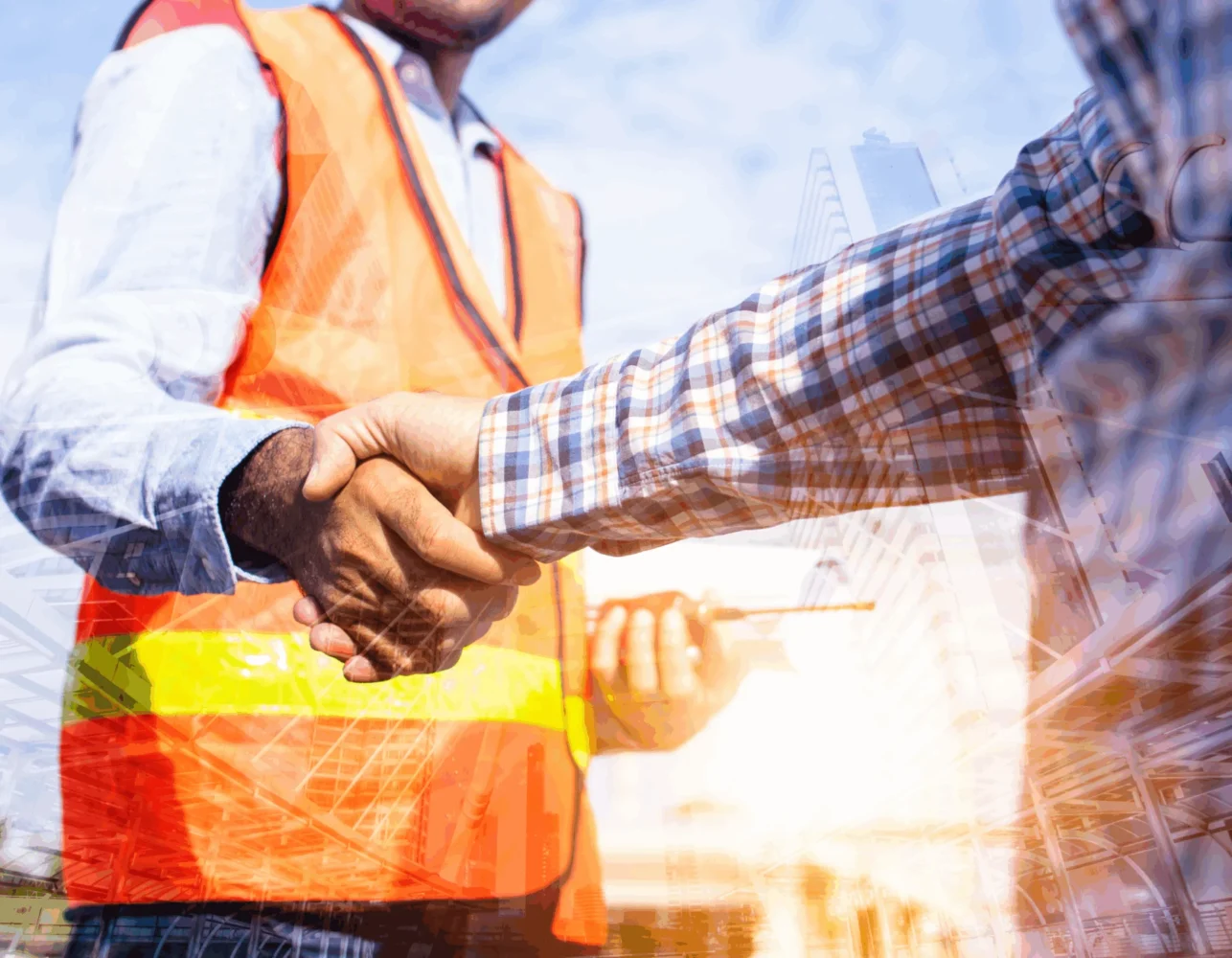 Handshake of construction workers wearing safety vests with backdrop of building and infrastructure