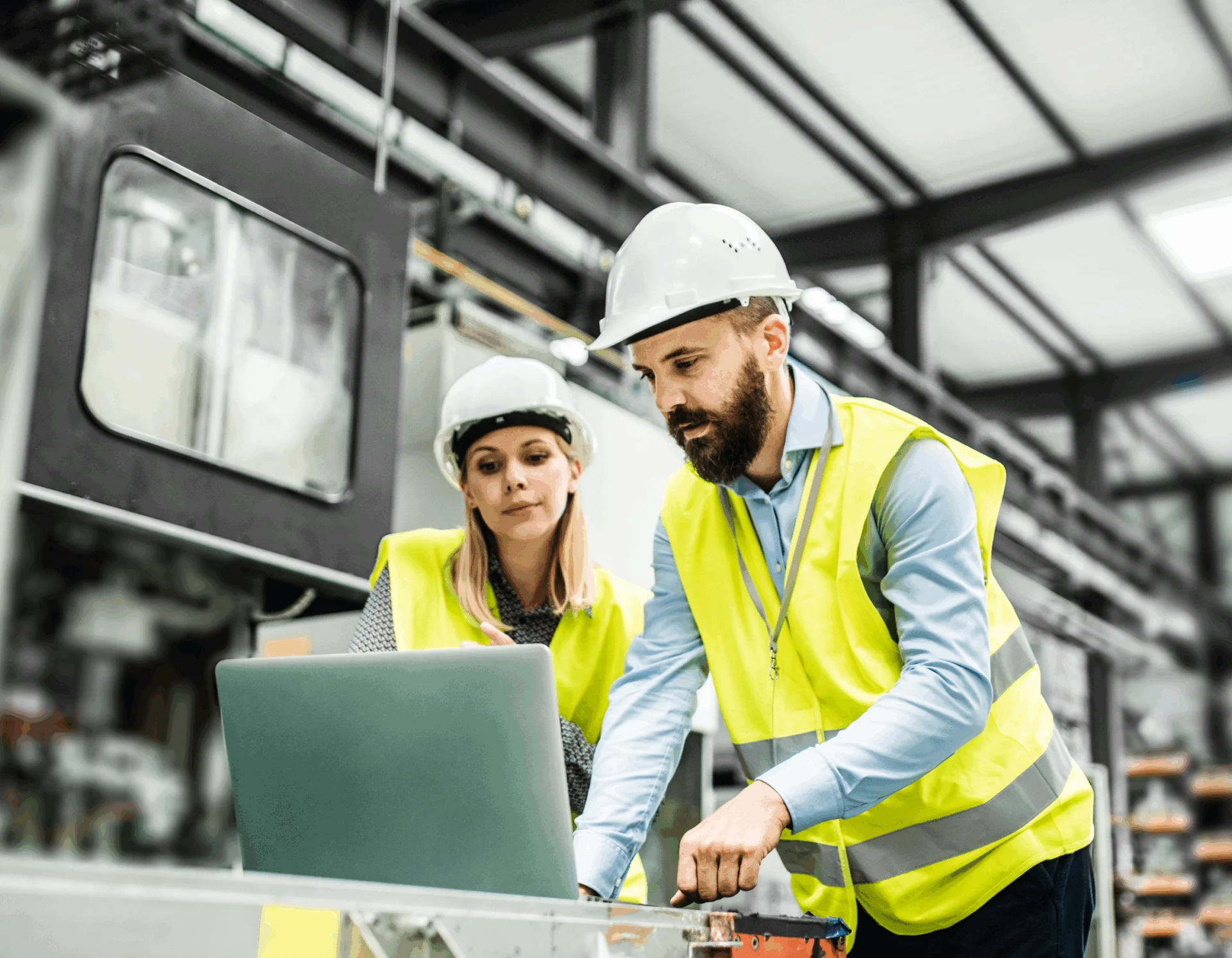Pair in safety attire review laptop in warehouse