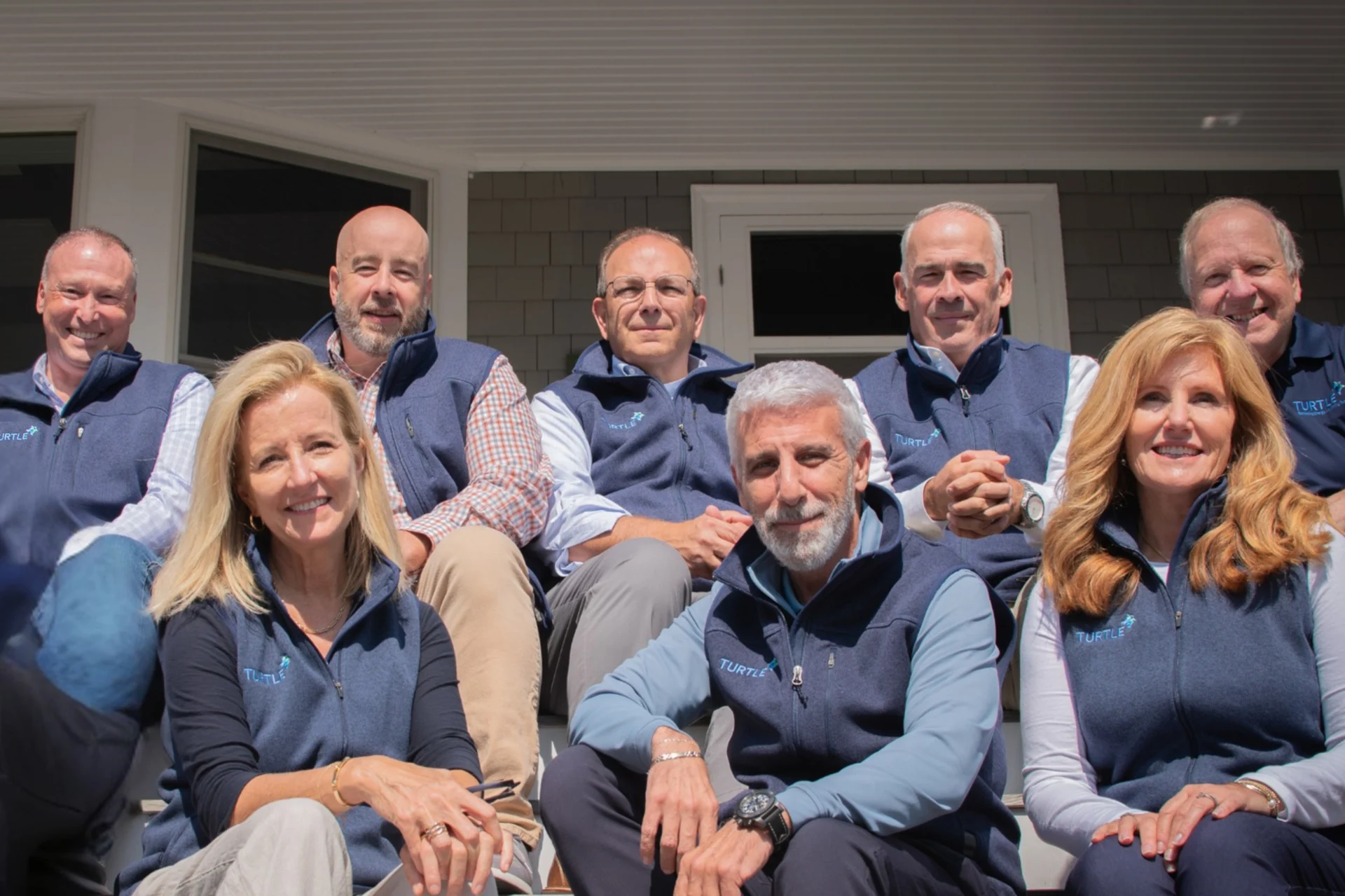 Group Photo of the leadership of Turtle Company sat together with branded vests