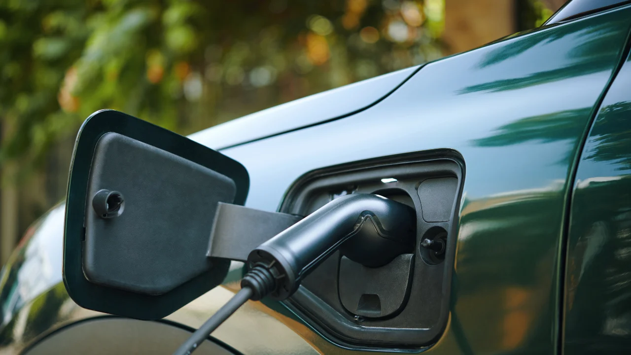 Electric vehicle charging port connected to a charging cable on a parked EV.