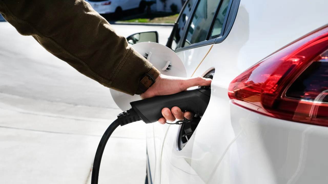 Male hand charging his white electric vehicle.